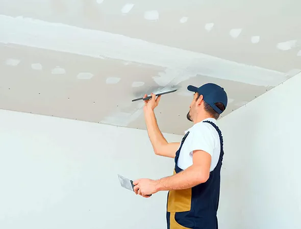 Professional drywall and wall repair service in Anchorville, MI featuring a technician patching and smoothing a ceiling.