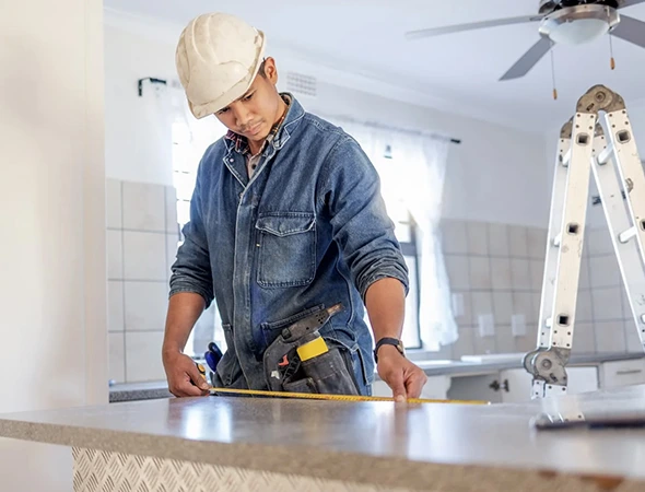 Countertop and surface repairs in Algonac, MI featuring a handyman measuring a kitchen island for renovation.