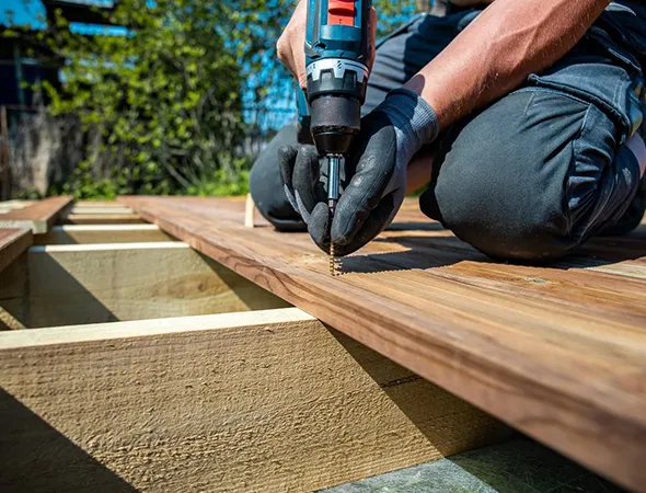 A covered outdoor patio with ceiling fans, wicker chairs with blue cushions, and glass windows.